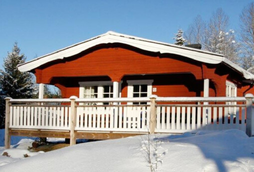 Röd stuga i snölandskap.