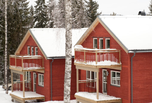 Röda stugor i vinterlandskap.