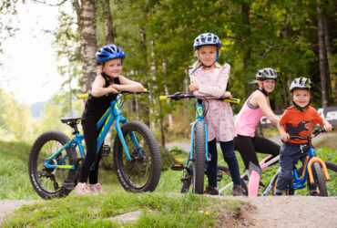 Barn poserar vid cyklar.