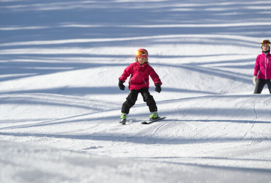 Barn plogar med skidorna i skidbacken.