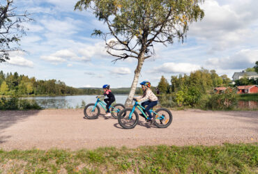 Barn cyklar vid sjö.