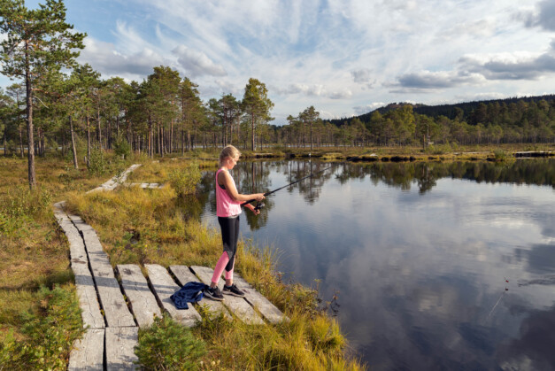 Flicka fiskar vid sjö.