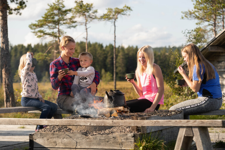 Familj på utflykt med picknick vid rastplats i skogen.