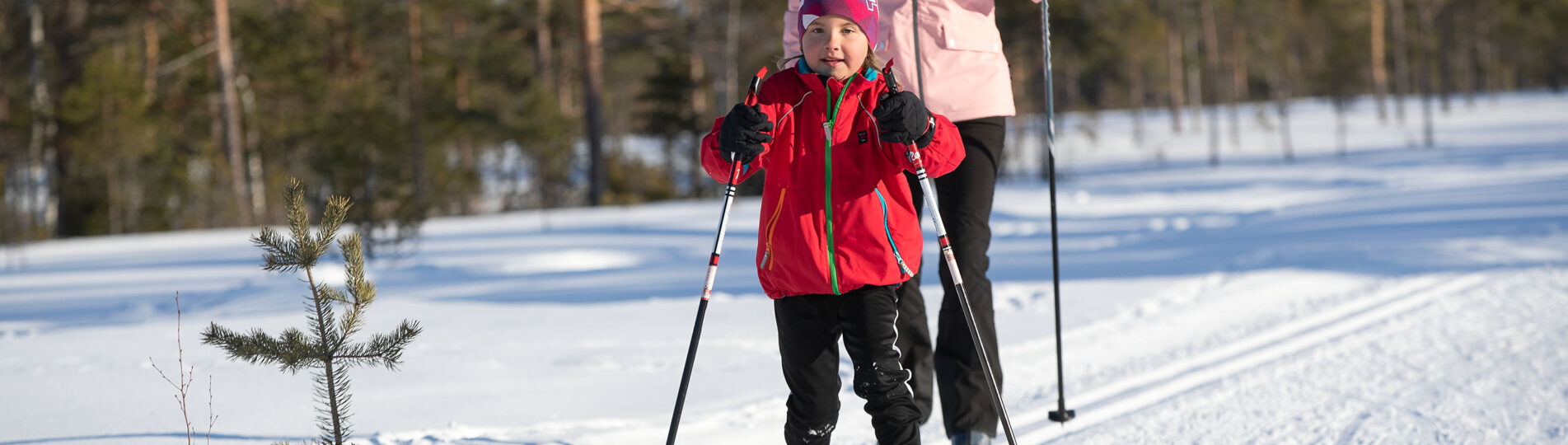 Flicka åker längdskidor tillsammans med mamma.