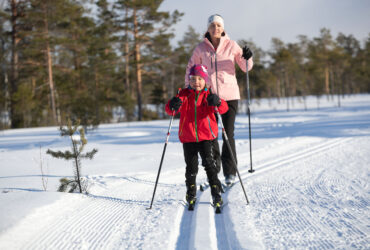 Flicka åker längdskidor tillsammans med mamma.