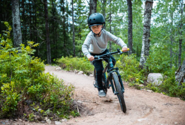 Pojke in action cyklar terrängbana i skog.