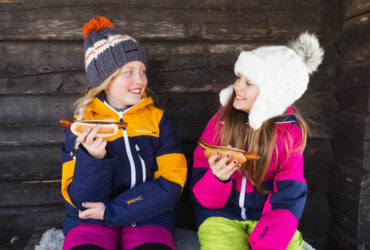 Flickor på klassresor äter varmkorv utomhus vinter.