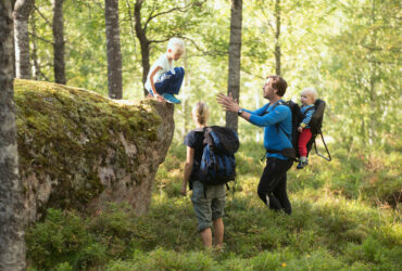 Familj på utflykt med ryggsäck vandrar i skog.