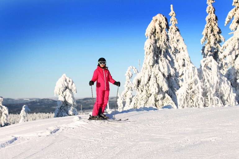 Kvinna på skidor på toppen av skidbacke.