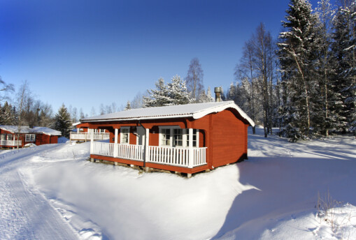 Röda stugor i vinterlandskap.