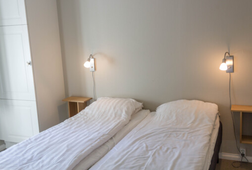 Enkelt inrett sovrum med enkelsängar i stuga.