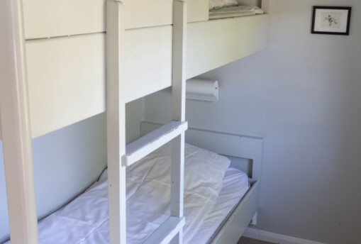 Våningssäng i vitmålat sovrum i stuga.