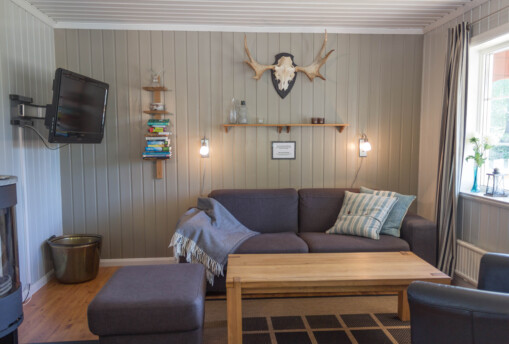 Vardagsrum i stuga med älghorn på väggen.