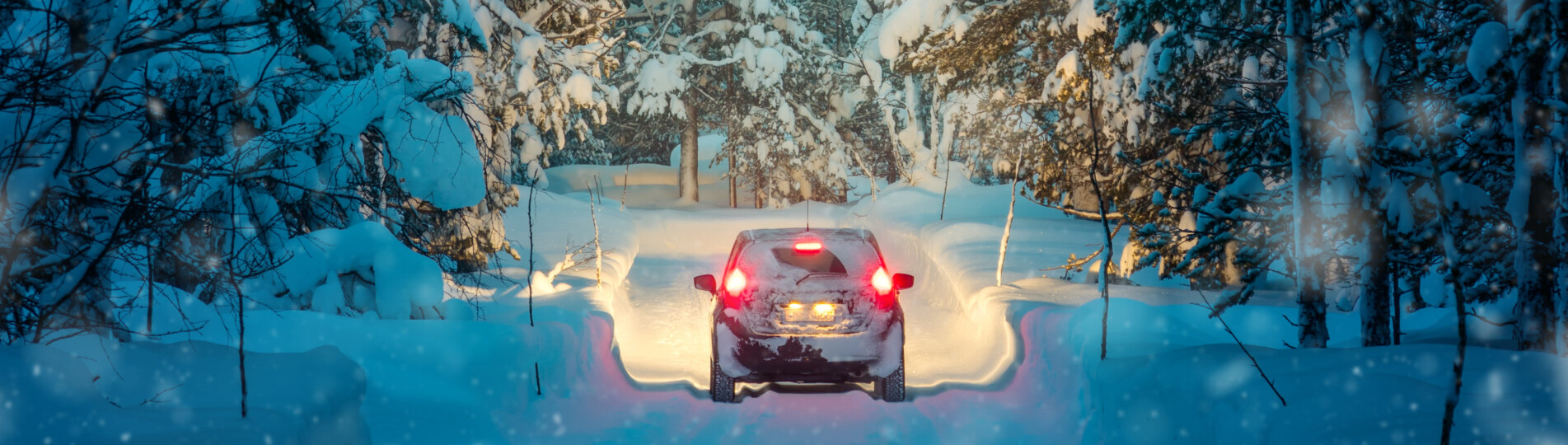 Bil kör genom snölandskap.