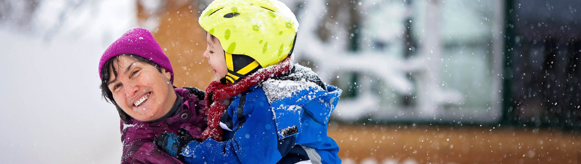 Glad mormor i lila jacka kramar barnbarn med gul hjälm