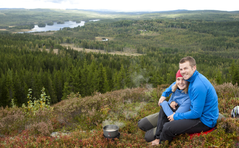 Par sitter tillsammans på en bergstopp med utsikt över skog