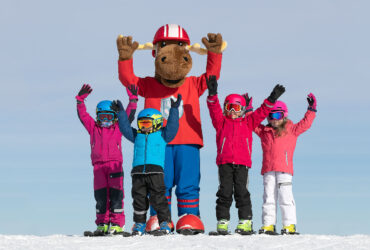 Skidåkande barn och Säfsen Resorts maskot älgen Filurius.