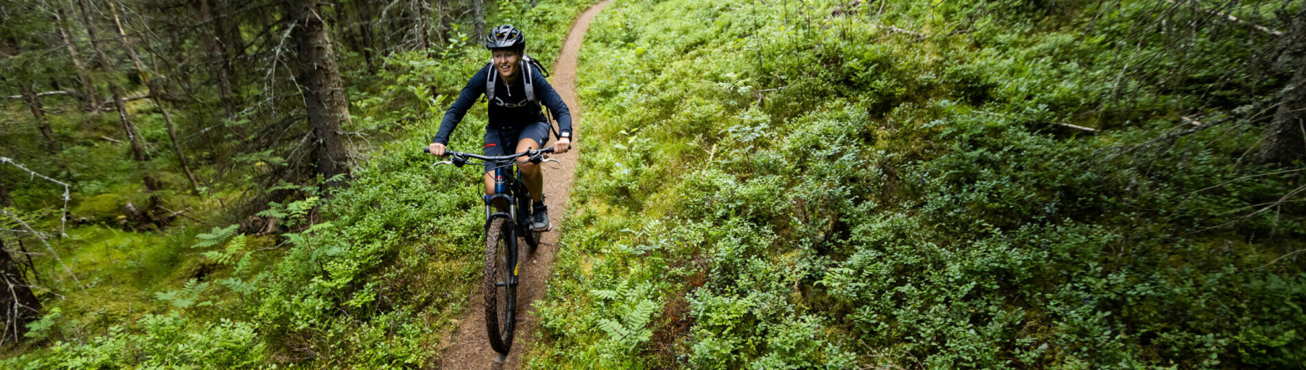 Kvinna cyklar i lummig skog i Säfsen-7892