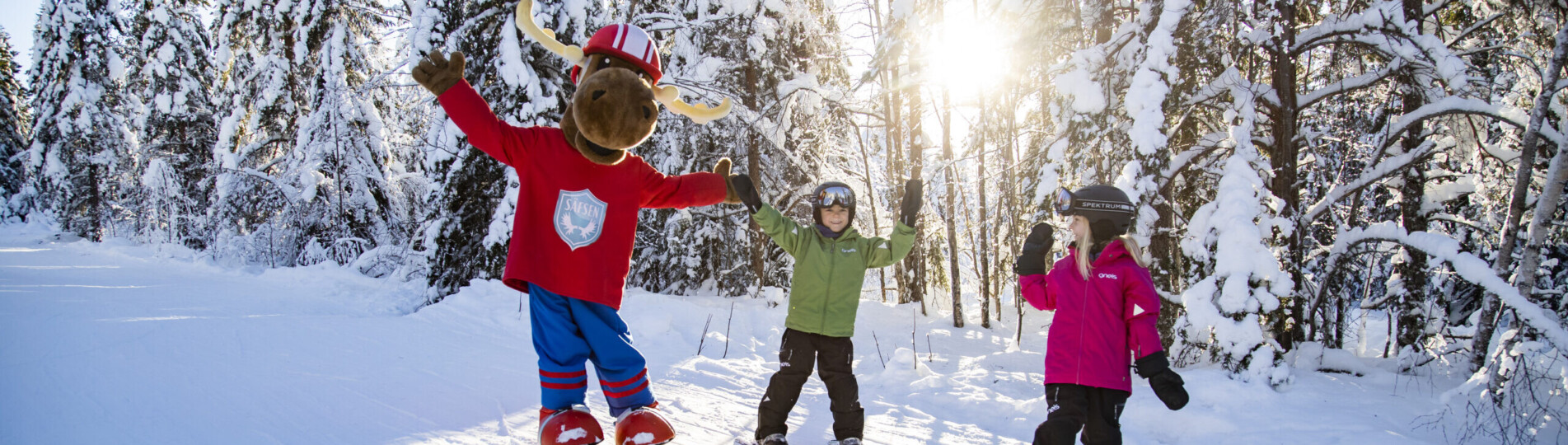 Älgen Filurius med barn i en solig skidbacke